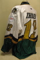 John Zeiler #12 White 2001-02. Clark Cup Championship season.  Worn by second year grinder John Zeiler. This season saw the jerseys go to a "Dazzel" type material. They proved less that durable and were replaced the following season by the traditional material. Front tie, shoulder patches, USHL crest and AMC memorial patch added half way through the season. This one has the greatest wear ever!!! One of my favs!!!. Made by OT Sports